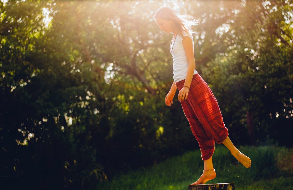 A woman balancing barefoot on a wood illustrating barefoot minimalist shoes lifestyle