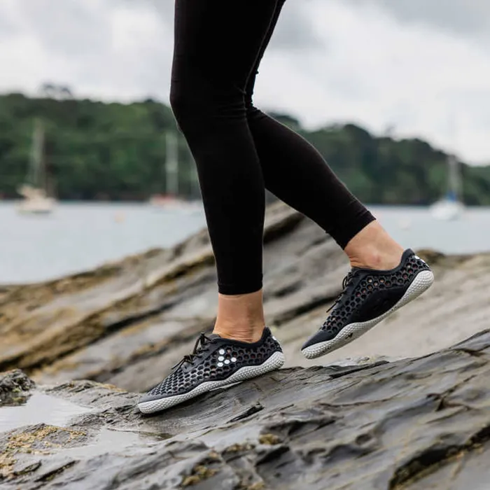 woman walking on rocks in vivobarefoot shoes