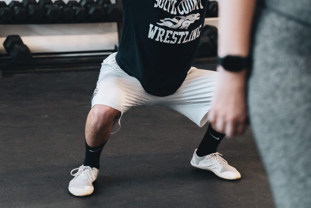Man squatting knees over toes in vivobarefoot shoes Man squatting knees over toes in vivobarefoot shoes