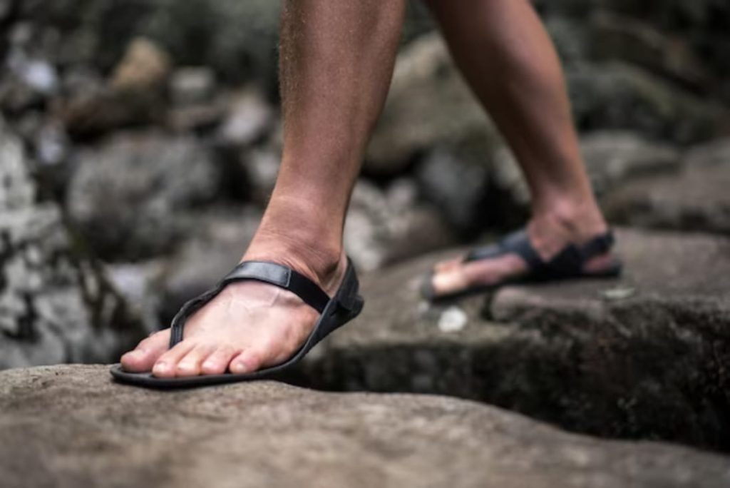 man's feet in barefoot sandals walking on stones