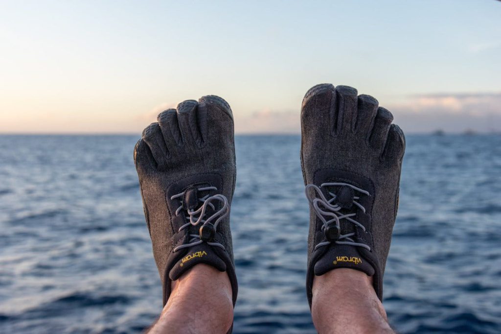 vibram fivefingers on a man's feet with an ocean in the background